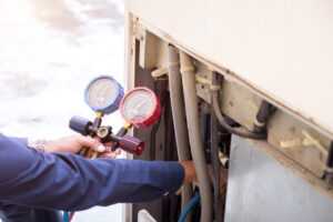 A man in a blue shirt holds a hose and a gauge, preparing for a task that requires precise measurement and control.