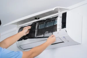 A technician repairs an air conditioner, focused on ensuring optimal performance and comfort in the environment.